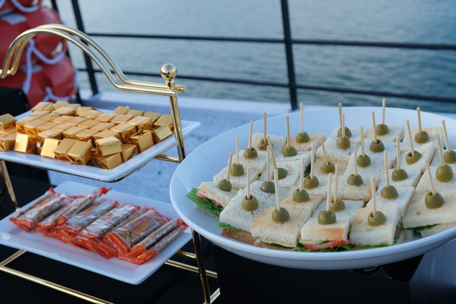 A buffet table with various food items including sandwiches, chocolates, and seafood.
