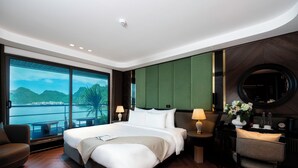 Habitación de hotel moderna con una cama grande, un escritorio, una silla, vista al agua y una pared de acento verde.