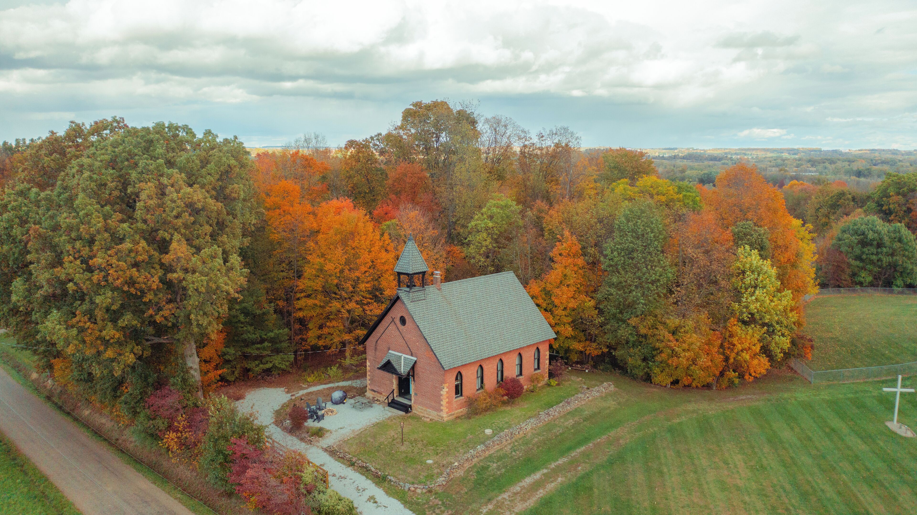 A small brick church surrounded by autumn foliage.