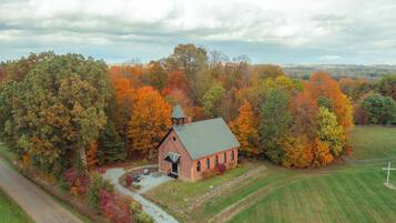 A small brick church surrounded by autumn foliage.