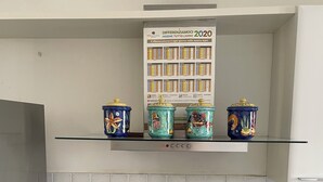 Una cocina con estufa a gas, cafetera y recipientes de cerámica decorativos en un estante.