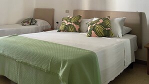 Un dormitorio con cama, dos almohadas, una mesita de noche y una lámpara colgante.