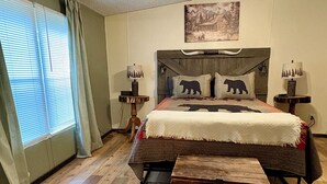 Un dormitorio con una cama de madera, un cabecero con motivo de oso, dos lámparas de noche, un ventilador de techo, una ventana con persianas y una alfombra con estampados de animales.