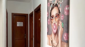 Un couloir avec des portes en bois et un grand tableau accroché au mur.
