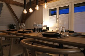 A dining area with a wooden table, chairs, and hanging light fixtures. - Little Nest - Nature & tranquillity between lakes & castles (Teufenthal)
