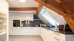 Een moderne keuken met witte kasten, een zwart aanrecht en een dakraam.