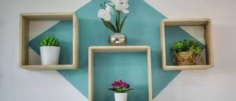 Three wall-mounted wooden shelves with potted plants and flowers.