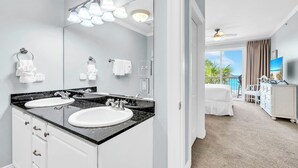Ein modernes Badezimmer mit zwei Waschbecken, einem großen Spiegel und einem Deckenventilator.