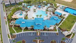 An aerial view of a resort with a central building, a swimming pool, and a basketball court.