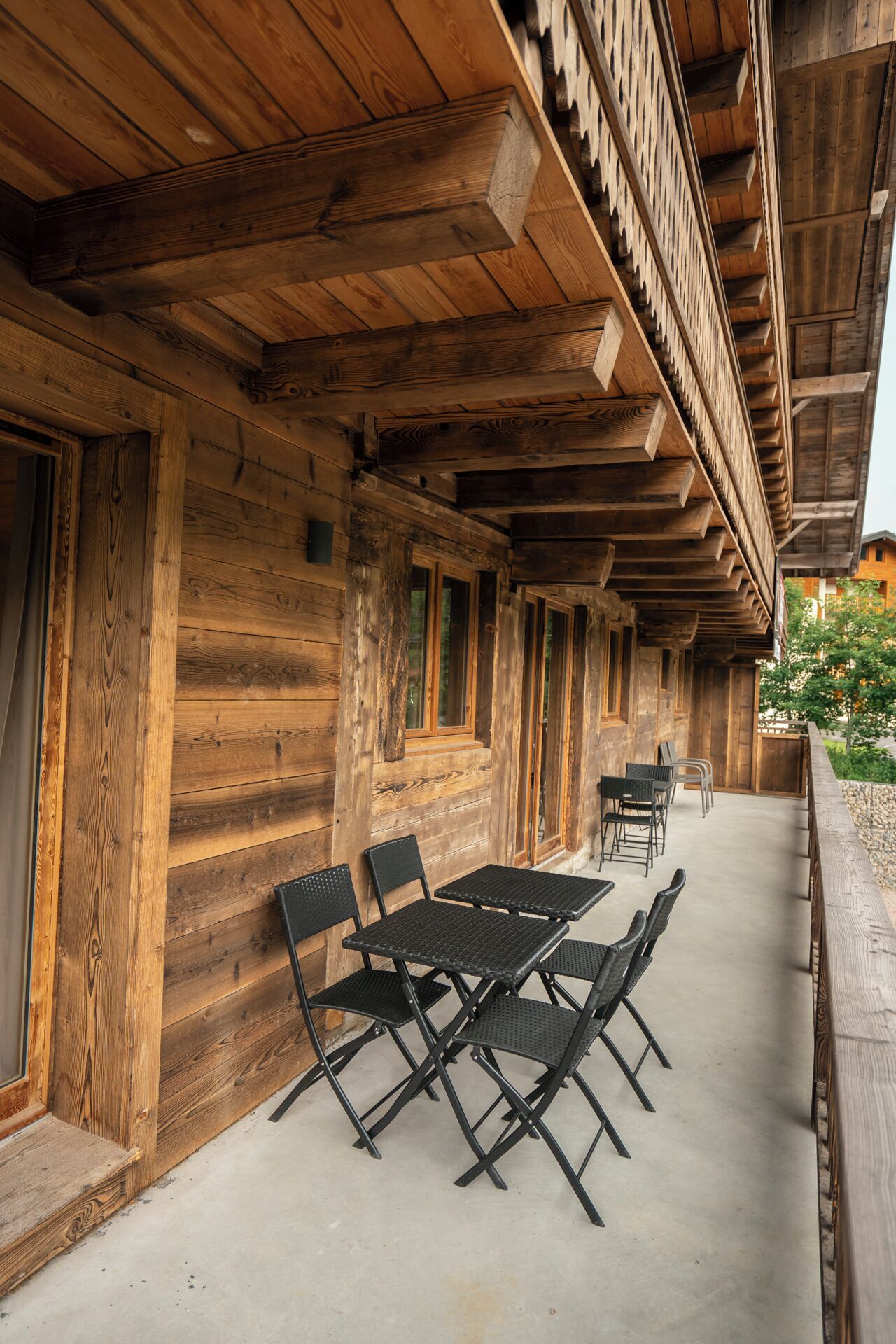A wooden building with a covered patio area featuring a table and chairs.