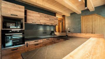 A modern kitchen with wooden cabinets, a large island, and built-in appliances.