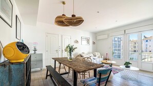 A spacious dining area with a wooden table, benches, and a yellow speaker. - Cozy 2 Bedroom Apartment in the Heart of Cannes (Cannes)
