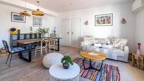 A modern living room with a sofa, coffee table, dining table, chairs, and a potted plant. - Cozy 2 Bedroom Apartment in the Heart of Cannes (Cannes)