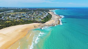 An aerial view of Blue Cottages, featuring a beachfront property with a mix of residential buildings and natural landscapes. - Blue Cottage – 3 Min Walk to Beach | Sleeps 11 | Pet Friendly (Ulladulla)