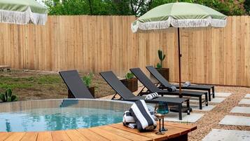 A pool area with lounge chairs, a wooden deck, and a cactus plant.