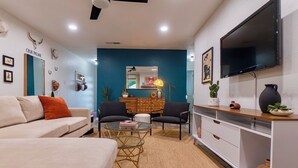 Una sala moderna con un sofá, dos sillones, una mesa de centro, un televisor y un aparador.