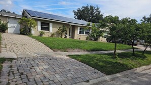 Ein Wohnhaus mit befestigter Auffahrt, Solaranlage auf dem Dach und einem gepflegten Rasen.