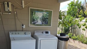 Ein Waschraum mit zwei weißen Waschmaschinen, einem Warmwasserbereiter und einer wandmontierten Klimaanlage.