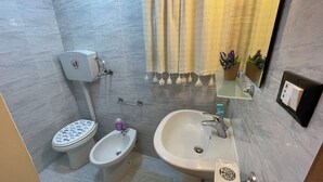 Une salle de bain équipée de toilettes, d’un bidet, d’un lavabo et d’un miroir.