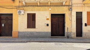 Une rangée de trois portes avec des volets marron, portant les numéros 13, 15 et 17, et un petit appareil de climatisation fixé au mur.