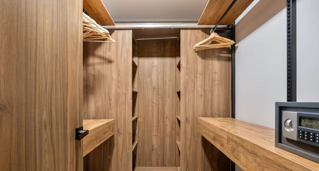 A walk-in closet with wooden shelving and a digital lock.