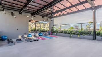 An indoor gym with exercise equipment, a large window, and a view of buildings.