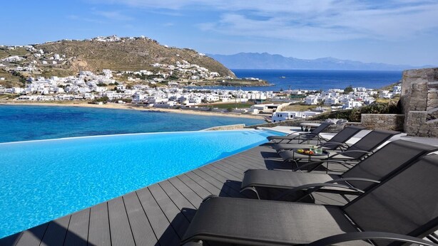 Zona de piscina con sillones de descanso y vistas a un pueblo costero.