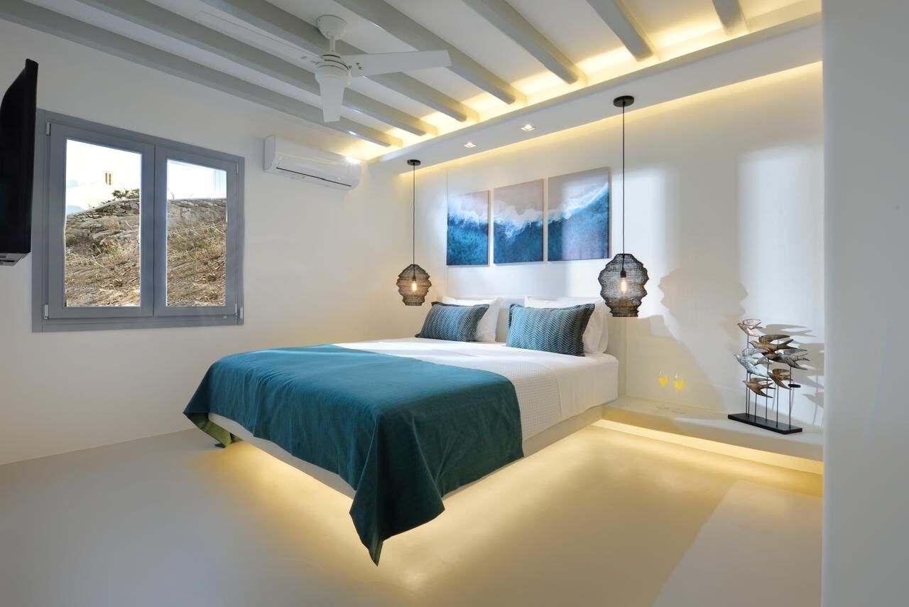 A modern bedroom with a bed, a window, artwork, and a ceiling fan.