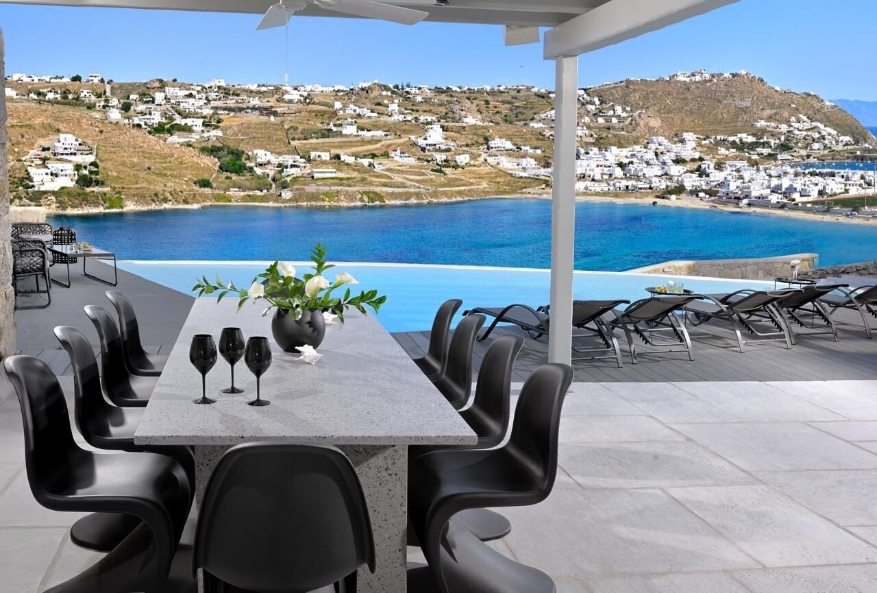An outdoor dining area with a view of a coastal town and the sea.