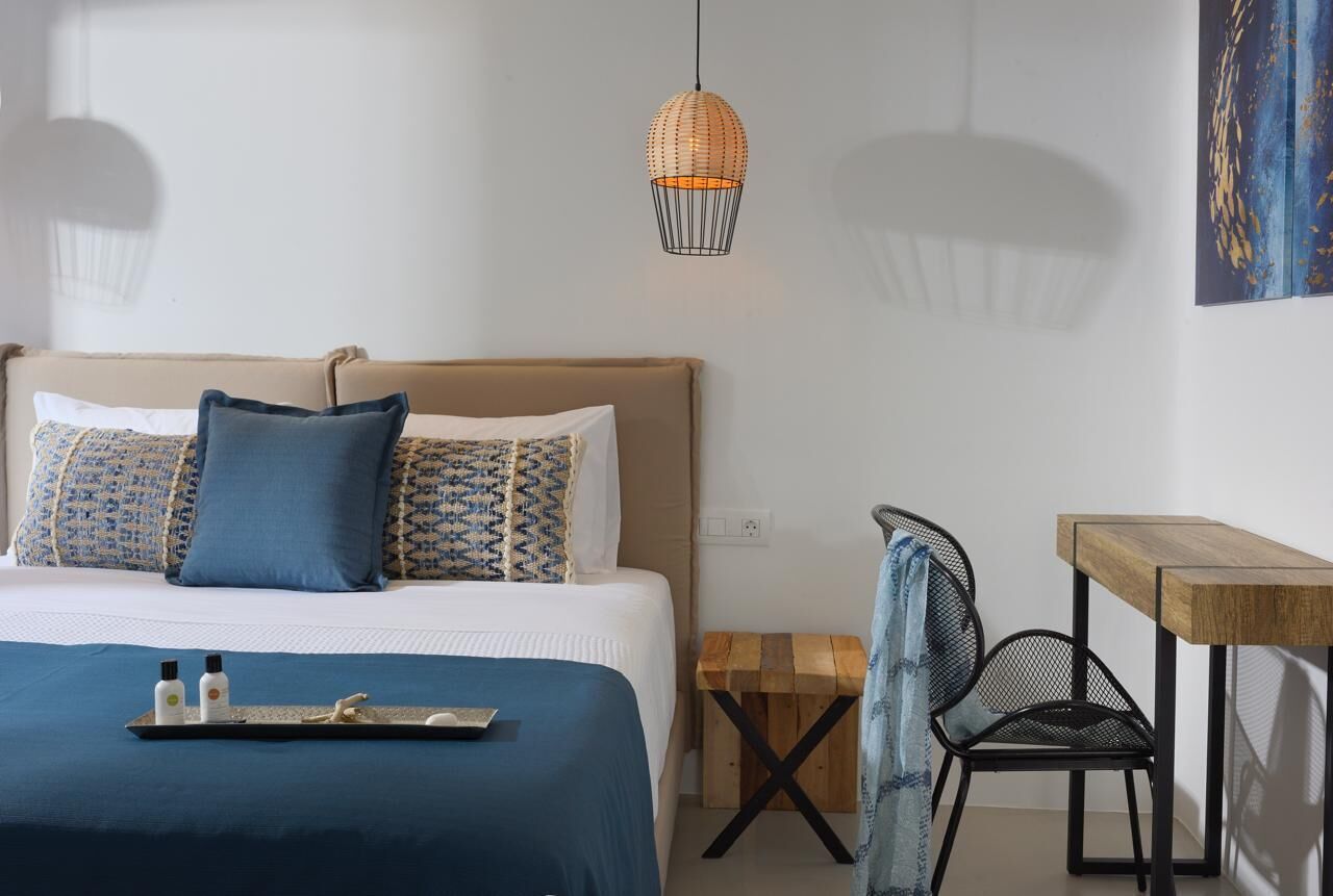 A bedroom with a bed, a wooden side table, a chair, and a hanging light fixture.