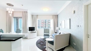 A modern living room with a sofa, a dining table, and a TV. - Elegant 2-bed Retreat Stunning Downtown Views (Dubai)