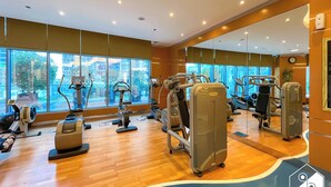 A gym with various exercise machines, large windows, and a mirror reflecting the equipment. - Elegant 2-bed Retreat Stunning Downtown Views (Dubai)