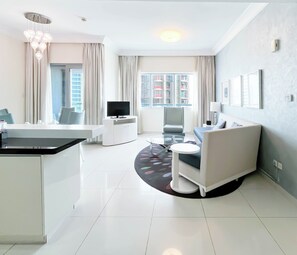 A modern living room with a sofa, a dining table, and a TV. - Elegant 2-bed Retreat Stunning Downtown Views (Dubai)