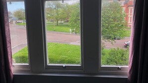 A window with a view of a street, greenery, and buildings. - Green Lodge (Liverpool)