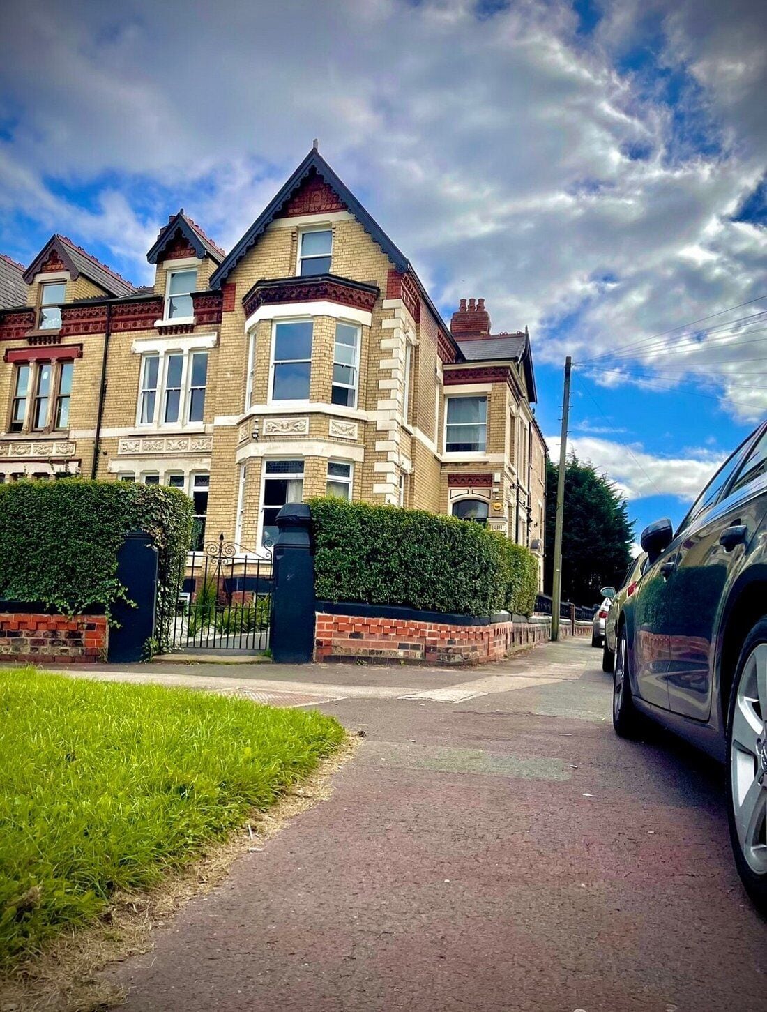A row of terraced houses with a paved driveway and a parked car.