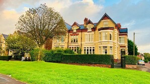 A Victorian-style house with a prominent bay window, a well-maintained lawn, and a traditional brick facade. - Green Lodge (Liverpool)