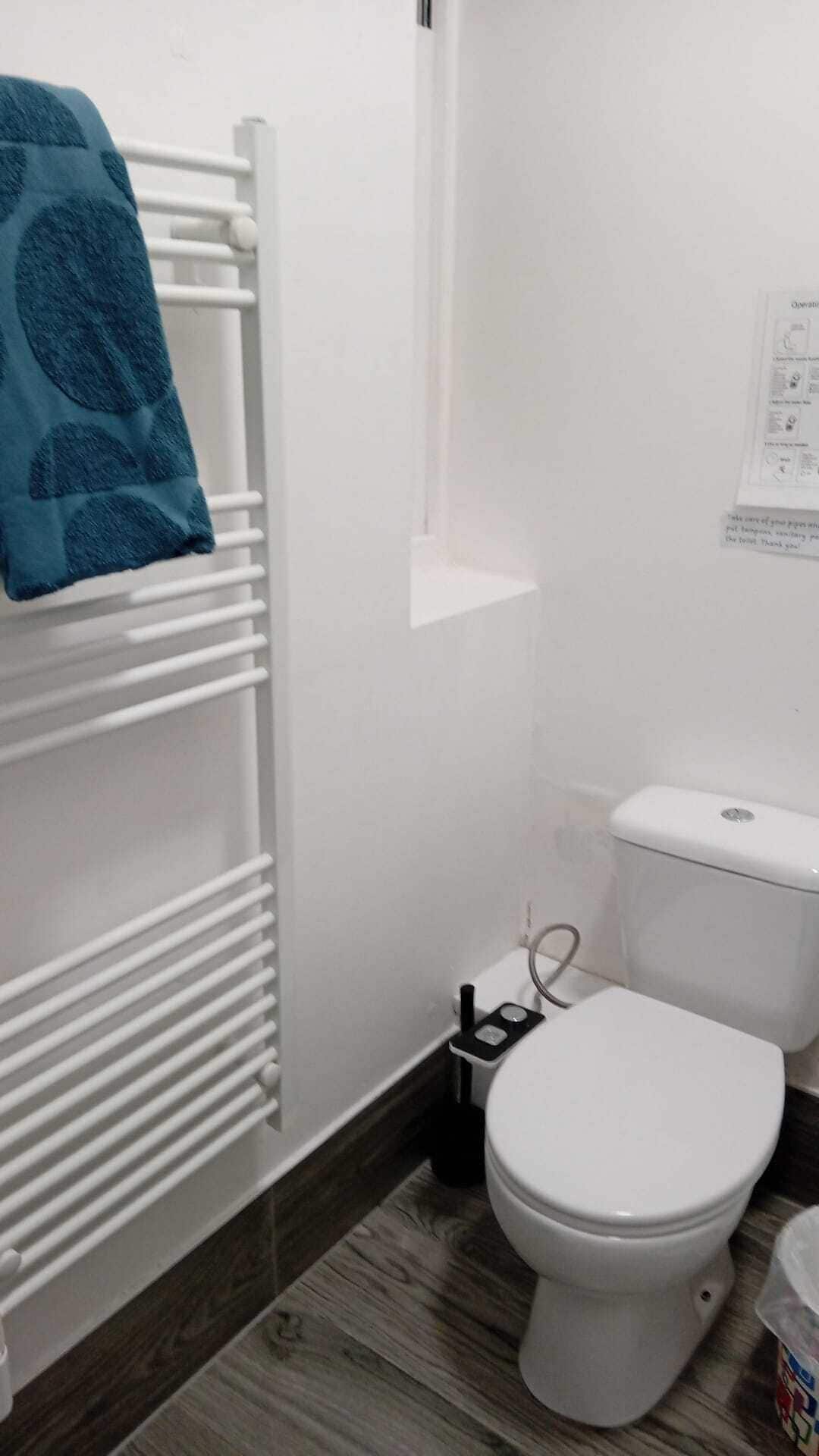A bathroom with a white radiator, a white toilet, and a blue towel on the radiator.