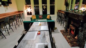 A cozy living room with a green sofa, a fireplace, and a dining area with a long table. - Green Lodge (Liverpool)