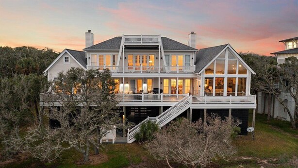 A large, two-story house with a balcony, a covered porch, and a staircase leading to the main entrance.