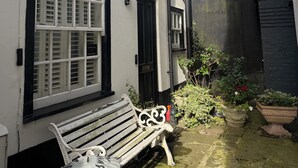 Un callejón estrecho con un banco, un contenedor de basura y plantas en macetas.