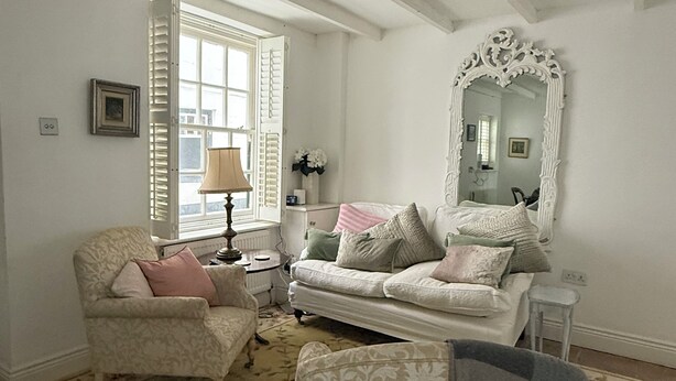 Una sala de estar con sofá, sillón y un espejo grande.