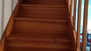 A wooden staircase with a handrail, leading to a landing.