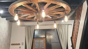 A rustic interior with exposed wooden beams, a wooden ceiling fan with light bulbs, and a wooden door with glass panels. - The Hurst Stable, 1800 century Coach House offering luxurious amenities, Hottub (Wheaton Aston)