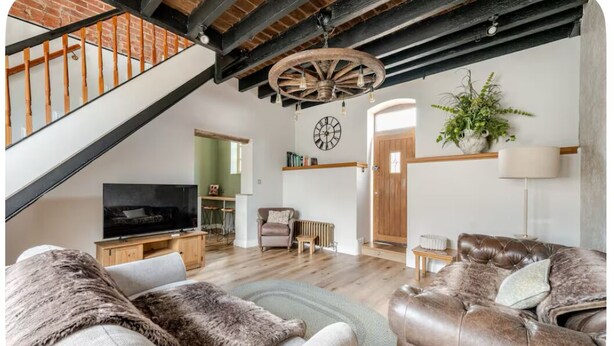 A spacious living room with a television, leather sofas, a wooden coffee table, and a rustic ceiling. - The Hurst Stable, 1800 century Coach House offering luxurious amenities, Hottub (Wheaton Aston)
