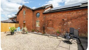 A brick building with a gravel yard, outdoor seating, and a solar panel on the roof. - The Hurst Stable, 1800 century Coach House offering luxurious amenities, Hottub (Wheaton Aston)