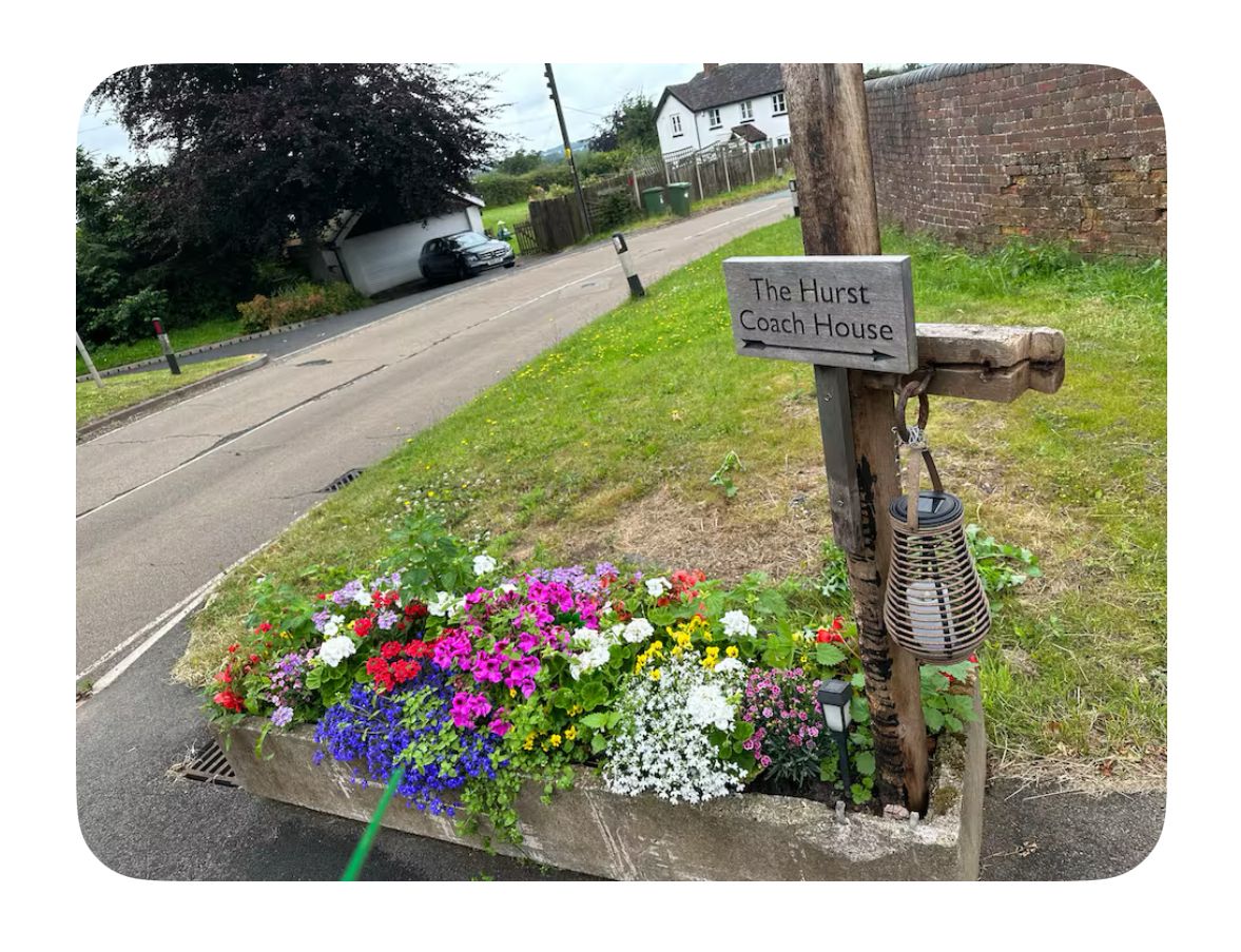 A sign for The Hurst Coach House with a flower bed in front.