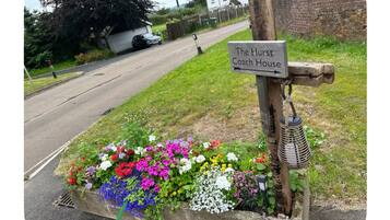 A sign for The Hurst Coach House with a flower bed in front.