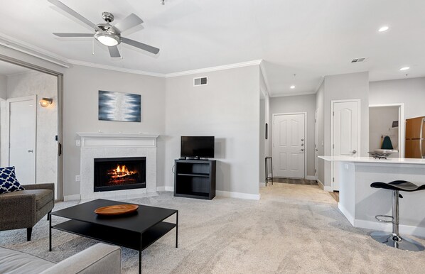 A modern living room with a fireplace, a TV, and a ceiling fan.