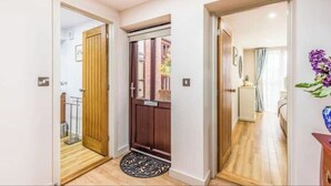 Un corridoio con pavimento in legno, una porta con un vetro e un piccolo tappeto.