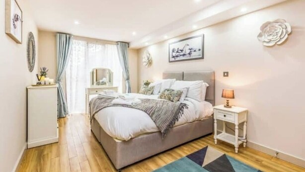 Una camera da letto con un letto, comodini, una cassettiera e una finestra con tende.